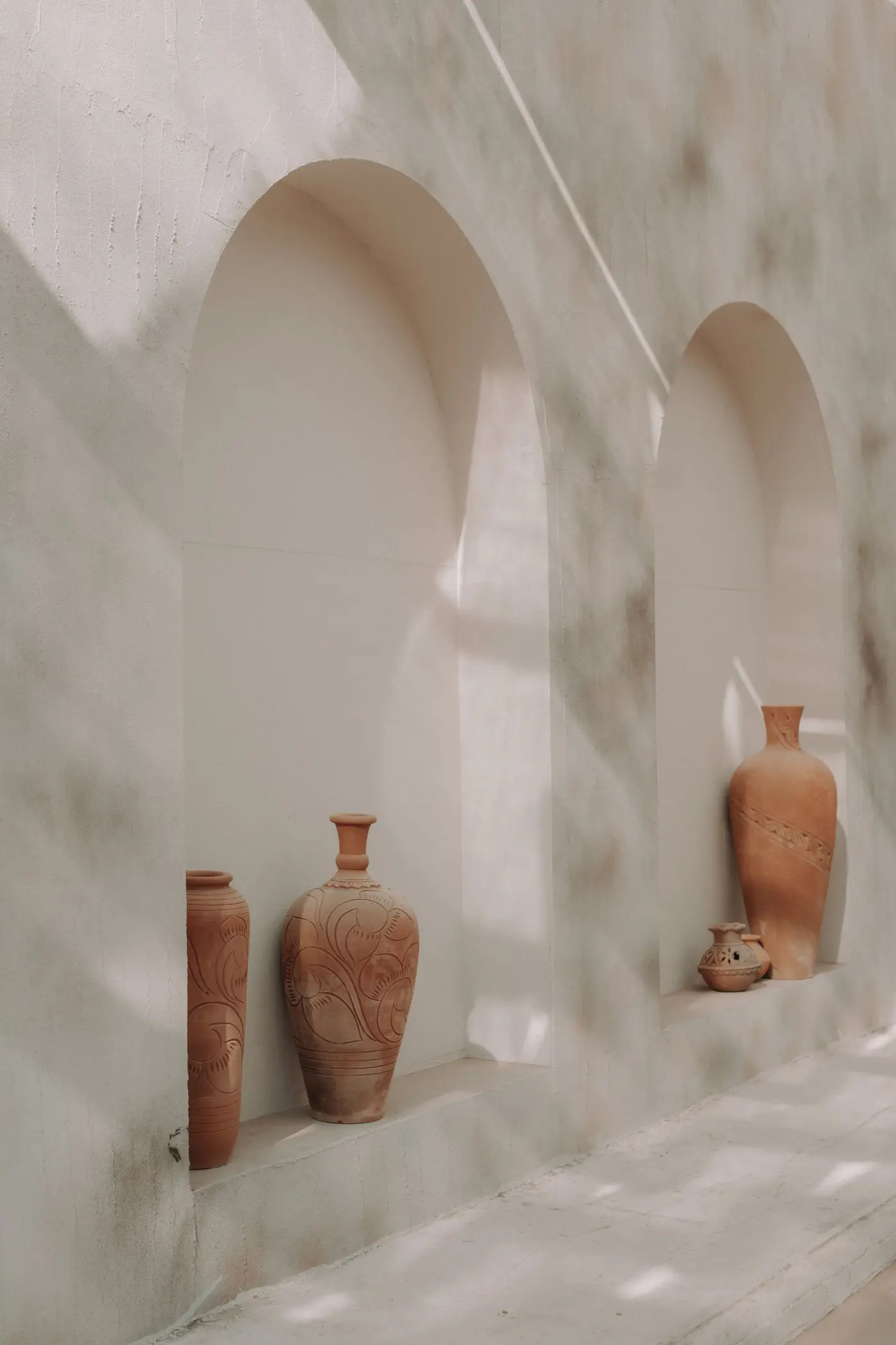 Terracotta vessels in a sunlit arched niche — reference photography for the material palette